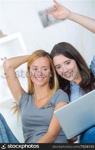 two cute girls with laptop on sofa
