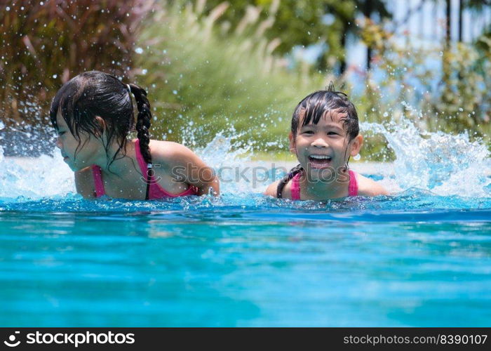 Two cute little girls playing in the pool. Summer lifestyle concept.