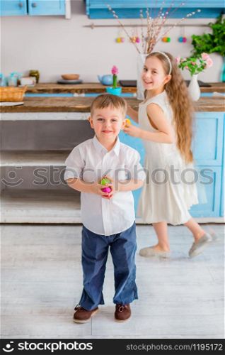 Two cute little kids with easter eggs having fun in the kitchen. Happy easter.. Two cute little kids with easter eggs having fun in the kitchen.