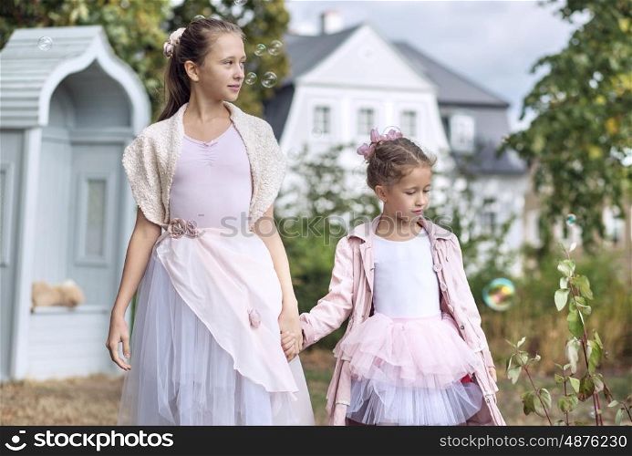 Two cute sisters walking in the autumnn garden