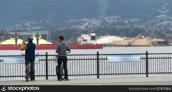 Two cyclists viewing Burrard Inlet, Vancouver, British Columbia, Canada