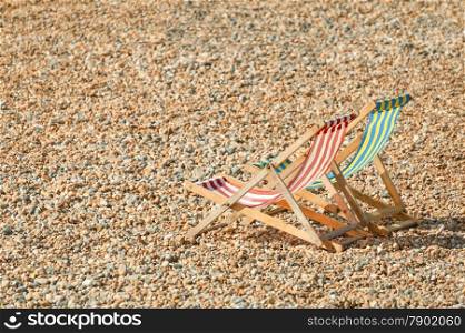 two deckchairs on a pebbled beach in summer