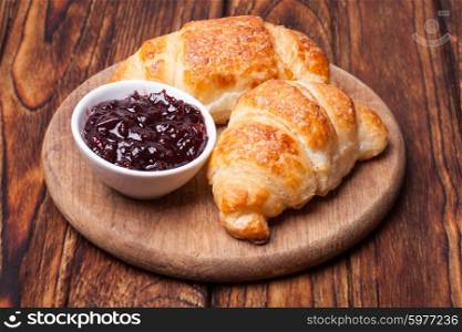 Two delicious croissants on a wooden cutting board. Breakfast with fresh croissants