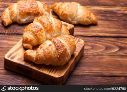 Two delicious croissants on a wooden cutting board. Breakfast with fresh croissants