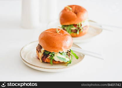 Two delicious homemade burgers with beef, cheese and vegetables on white wooden table