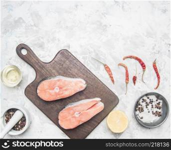 two delicious raw salmon steak with lemon, seasoning and pepper on a white background, place for text