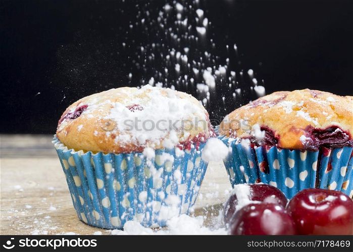 two delicious sweet muffins with cherry berries inside, food ready for eating close up, made at the factory and sprinkled with white icing sugar. two delicious sweet muffins