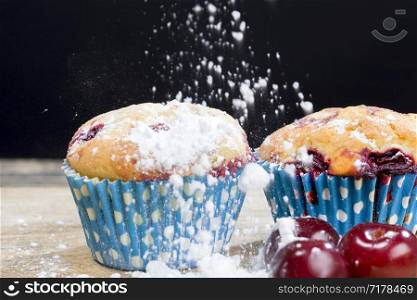 two delicious sweet muffins with cherry berries inside, food ready for eating close up, made at the factory and sprinkled with white icing sugar. two delicious sweet muffins