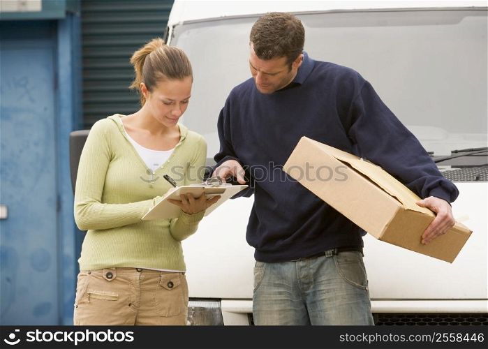 Two deliverypeople standing with van holding clipboard and box