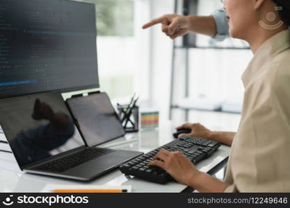 Two developer programmer checking code on multiple monitor while programming to developing website.