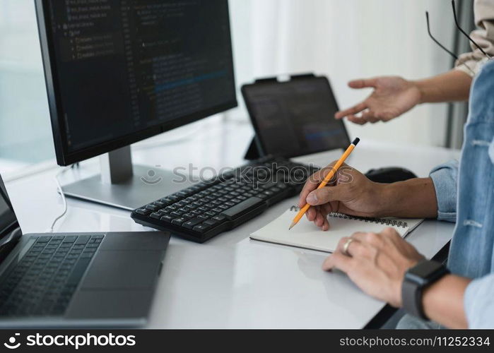 Two developer programmer writing notes while discussing about programming to developing website.