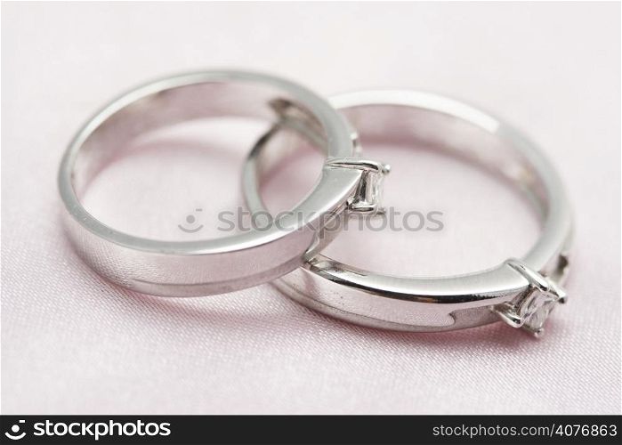 Two diamond wedding rings on a silver satin background