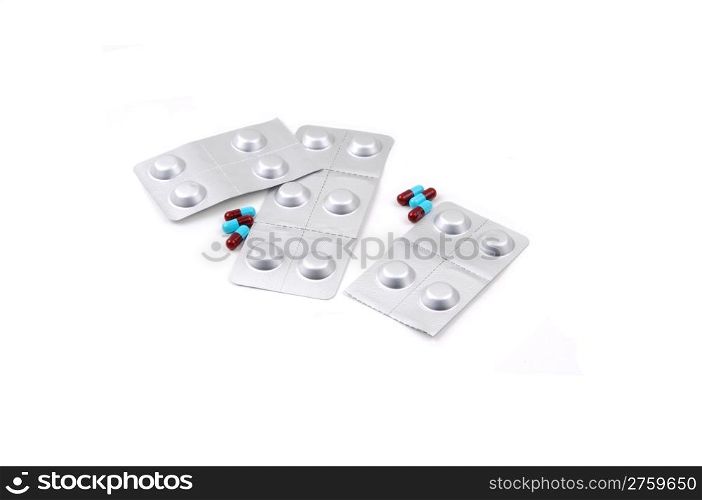 Two different kind of prescription medication, one a blue and burgundypill, the other one sealed in silver folia, on white background.