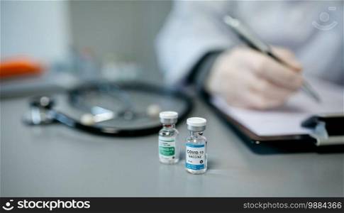 Two different vials of coronavirus vaccine on a female doctor’s table