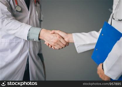 Two doctor shaking hands with working together.