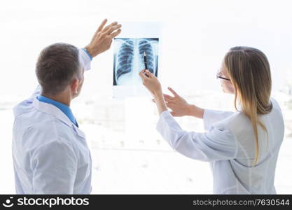 Two doctors examining a x-ray film by the window at clinical office. Doctors examining x-ray film