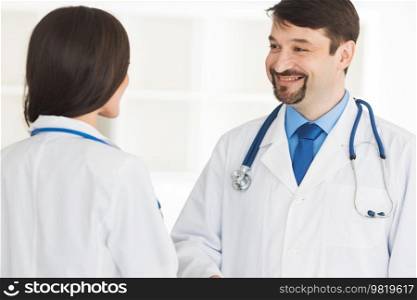 Two doctors talking and smiling, teamwork and healthcare. Two doctors talking