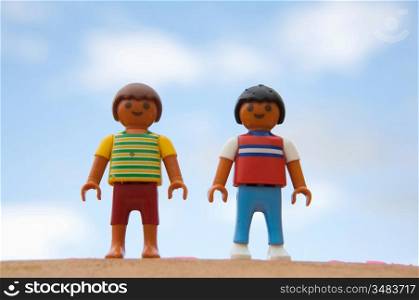 Two dolls standing on background with blue sky and clouds