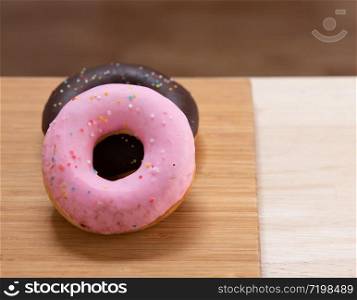 Two donuts are pink, Chocolate with sprinkles isolated on wood background.. Two donut isolated on wood background.