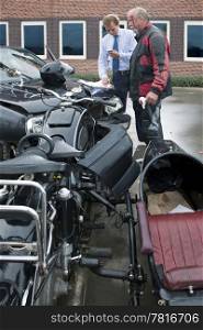 two drivers exchanging information for insurance purposes after a car crash involving a car and a classic sidecar motorcycle