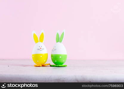 Two easter bunnies of colored eggs over white. Easter scene with colored eggs