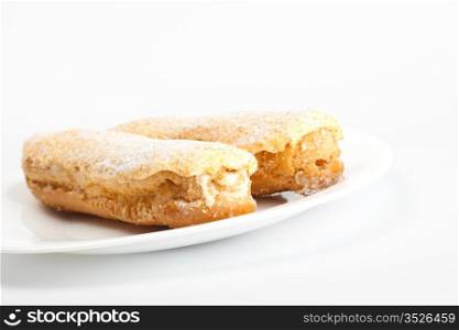 two eclairs on white dish, grey background
