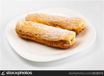 two eclairs on white dish grey background