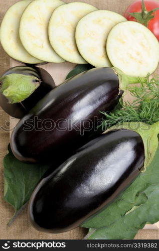 Two eggplants of black colour and the cut slices