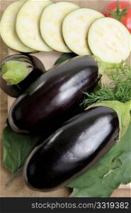 Two eggplants of black colour and the cut slices