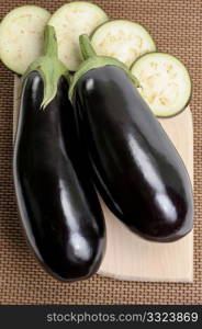 Two eggplants of black colour and the cut slices