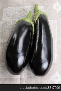 Two eggplants of black colour on a cloth.