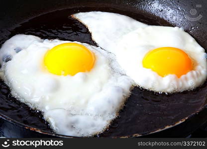 Two eggs frying in oil