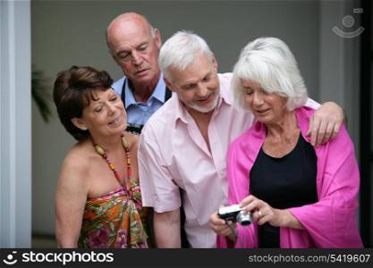 Two elderly couple looking at photos on digital camera