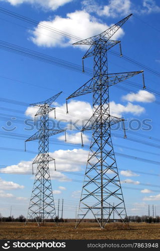 Two electrical transmission towers and power lines on cloudy sky.