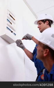 Two electrical workers installing fuse box