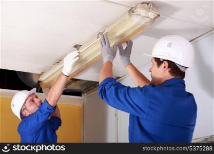 Two electrician repairing office lighting