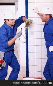Two electricians discussing a voltmeter