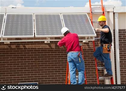 Two electricians installing solar panels on a building.