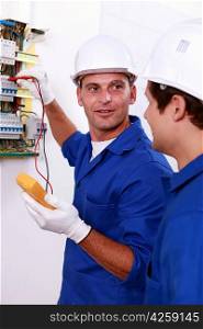 Two electricians testing fuse box