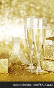 Two elegant flutes of sparkling champagne with decorative golden gifts