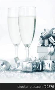 Two elegant flutes of sparkling champagne with decorative silver gifts