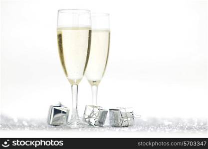 Two elegant flutes of sparkling champagne with decorative silver gifts