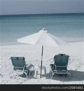Two empty chairs and a beach umbrella on the beach