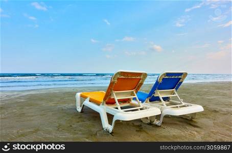 Two empty sunloungers on a sandy beach by the sea in the evening, Larnaca, Cyprus