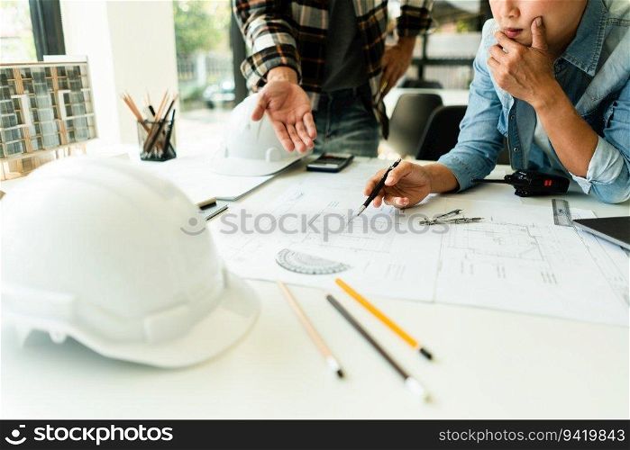 Two engineer working to discuss and brainstorming about blueprint of construction project in office.