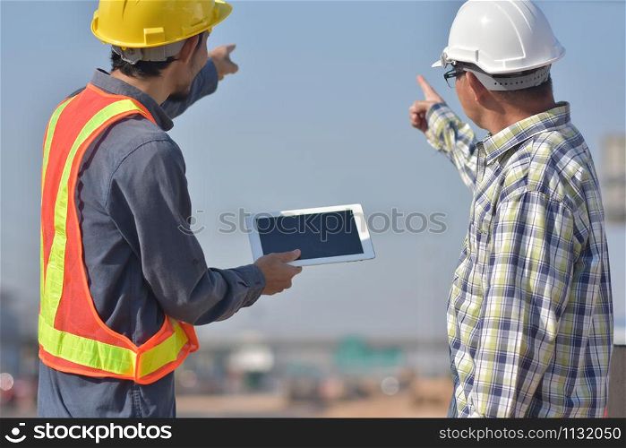 Two Engineering use tablet working road construction talking project management on work site