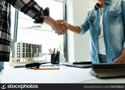 Two engineers shaking hand after working successful about brainstorming about construction project.