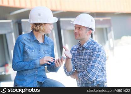 two engineers talking in front of building