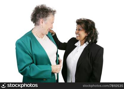 Two ethnically and age diverse female coworkers laughing together. Isolated on white with focus on the smaller woman.
