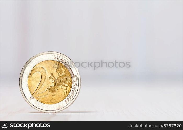 Two euros coin on white wood background. With copy-space for text